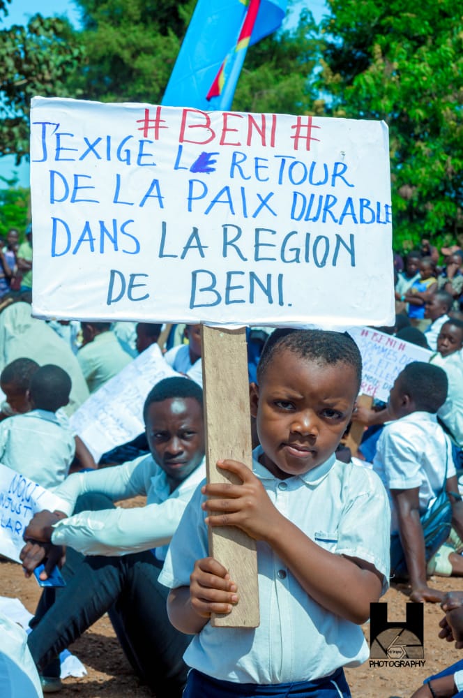 Un jeune garçon tient une pancarte