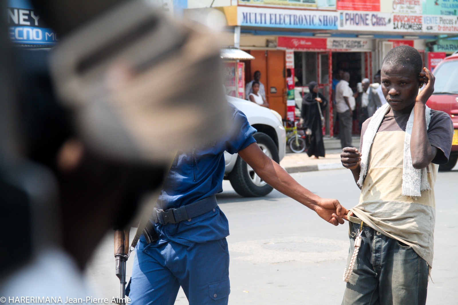 Un policier arrête un petit garçon vendeur ambulant dans une rue de Bujumbura