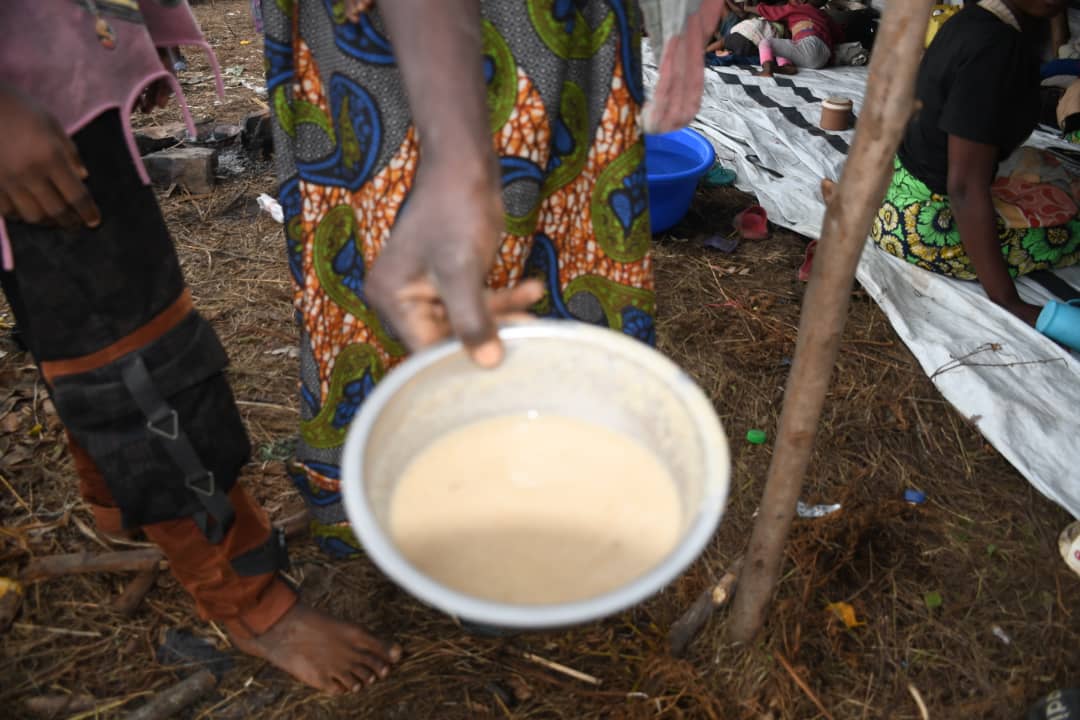Une mère congolaise à Busuma montre la très petite quantité de bouillie qu’une famille nombreuse est contrainte de partager, illustrant la gravité de la crise alimentaire dans le camp. Décembre 2025. © SOS Médias Burundi